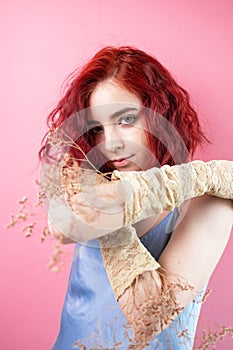 Beautiful curly haired European woman wears silk elegant dress with dried flowers on body awaits for spring coming