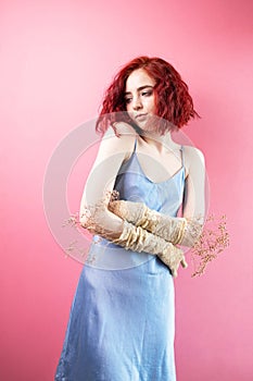 Beautiful curly haired European woman wears silk elegant dress with dried flowers on body awaits for spring coming