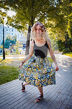 Beautiful curly haired woman curtsy in the city park