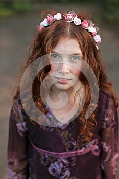 Beautiful curly teenage girl in a wreath of flowers