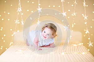 Beautiful curly toddler girl between Christmas lights