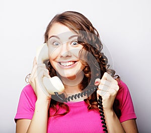 Beautiful curly woman talking on white vintage telephone