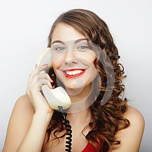 Beautiful curly woman talking on white vintage telephone