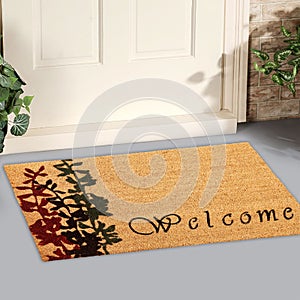 Beautiful cursive welcome peach color doormat with red and black flower plant Placed outside door with green leaves