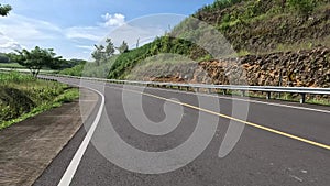 A beautiful curved road with hills on the side and blue sky in the background