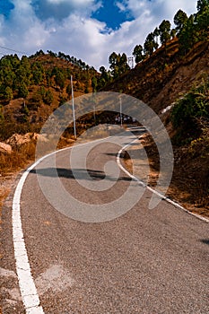Beautiful curved roadway, rocks, stones, blue sky with clouds.