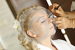 Beautiful, cute blond bride doing makeup before wedding day. Lon