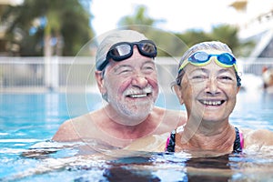 Beautiful and cute close up of two seniors in the pool having fun together - fitness and healthy lifestyle - summertime together