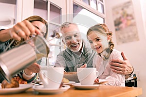 Beautiful cute dark-eyed granddaughter drinking tea in the morning