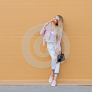 Beautiful cute funny amazing young hipster teen girl eating ice cream cone, laughs happy, bright casual wear, orange