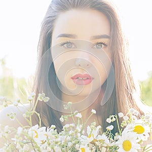 Beautiful cute girl with big lips and red lipstick with bared shoulders with a bouquet of daisies at sunset on a sunny warm