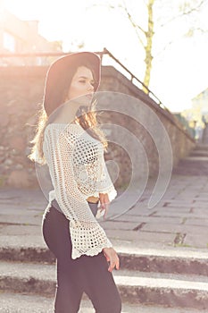 Beautiful cute girl with curly hair in a hat walking at sunset around the city