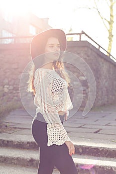 Beautiful cute girl with curly hair in a hat walking at sunset around the city