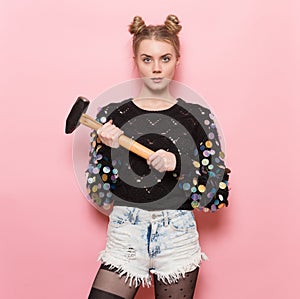 Beautiful cute girl holding heavy hammer in hands. Home repair and feminism concept