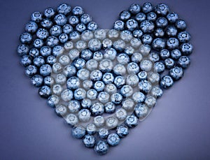 A beautiful cute heart made of whole juicy blueberries on a violet background. Berries full of vitamins. Healthy food.