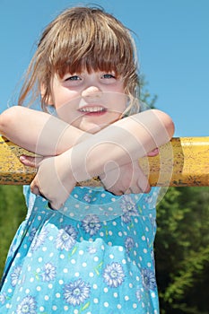 Beautiful cute little girl in blue dress rests hands