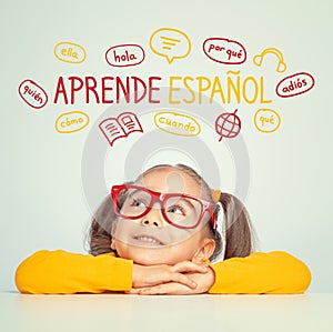 Beautiful cute little girl with eyeglasses looking at Learn Spanish text in Spanish and illustrations.