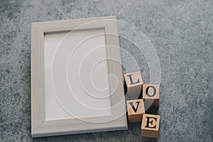 Beautiful cute lovely white pastel frame with wood cube LOVE letter on black background. Photo concept for couple and lover,family