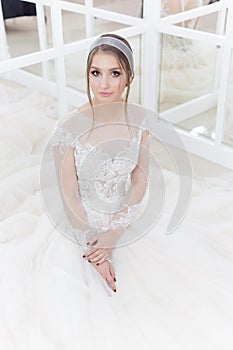 Beautiful cute tender young girl bride in wedding dress in mirrors with evening hair and gentle light make-up