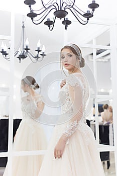 Beautiful cute tender young girl bride in wedding dress in mirrors with evening hair and gentle light make-up