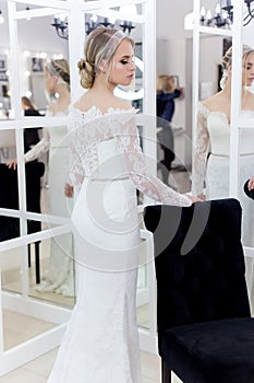 Beautiful cute tender young girl bride in wedding dress in mirrors with evening hair and gentle light make-up