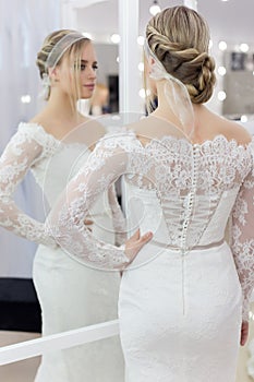 Beautiful cute tender young girl bride in wedding dress in mirrors with evening hair and gentle light make-up