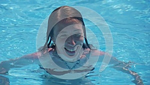 Beautiful cute woman enjoys water in swimming pool.