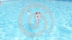 Beautiful cute woman enjoys water in swimming pool.