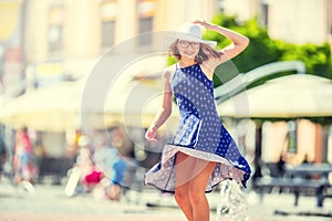 Beautiful cute young girl dancing on the street from happiness.Cute happy girl in summer clothes dancing in the sun