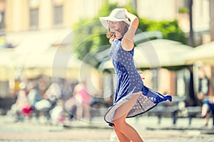 Beautiful cute young girl dancing on the street from happiness.Cute happy girl in summer clothes dancing in the sun