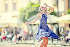 Beautiful cute young girl dancing on the street from happiness.Cute happy girl in summer clothes dancing in the sun