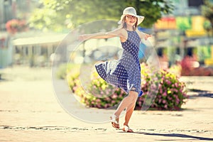 Beautiful cute young girl dancing on the street from happiness.Cute happy girl in summer clothes dancing in the sun