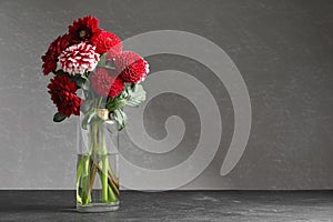 Beautiful dahlia flowers in vase on table against grey background. Space for text