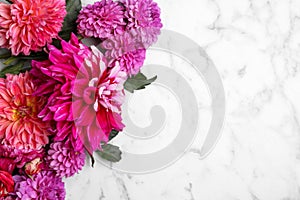 Beautiful dahlia flowers on white marble background, flat lay. Space for text