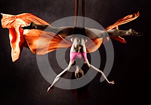 Beautiful dancer on aerial silk, graceful contortion, acrobat performs a trick on a ribbons