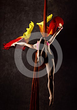 Beautiful dancer on aerial silk, graceful contortion, acrobat performs a trick on a ribbons