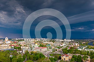 Beautiful dark blue thundercloud over the city. Top view of the city. Aerial photography. Houses, streets, green trees and parks.