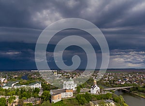 Beautiful dark blue thundercloud over the city. Top view of the city, churches, bridge, river.