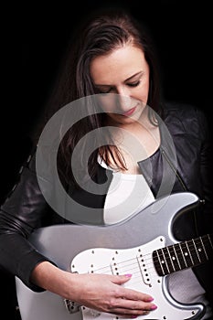 Beautiful dark girl playing guitar in rock style on a black background.