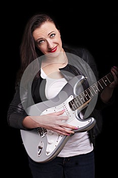 Beautiful dark girl playing guitar in rock style on a black background.