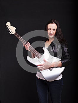 Beautiful dark girl playing guitar in rock style on a black background.