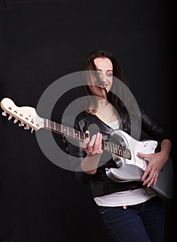 Beautiful dark girl playing guitar in rock style on a black background.