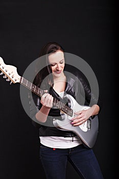 Beautiful dark girl playing guitar in rock style on a black background.