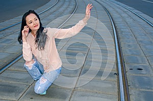 Beautiful dark-haired girl in a blouse and jeans posing on the tram tracks