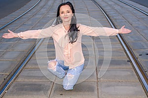 Beautiful dark-haired girl in a blouse and jeans posing on the tram tracks
