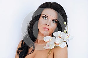 Beautiful dark haired girl with orchids on white