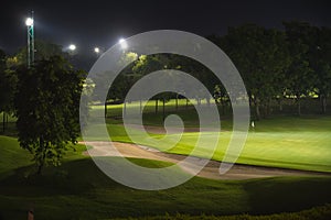 Beautiful dark night view of the golf course, Bunkers sand and green grass, garden background In the light of the spotlight