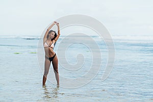 Beautiful dark skinned girl in swimwear resting on beach. African american model posing on tropical island