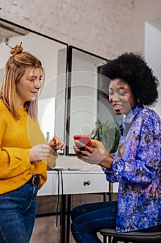 Beautiful dark-skinned and her fair-haired friend looking attentive