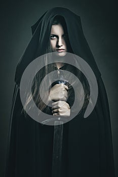 Beautiful dark woman with black robe and sword photo